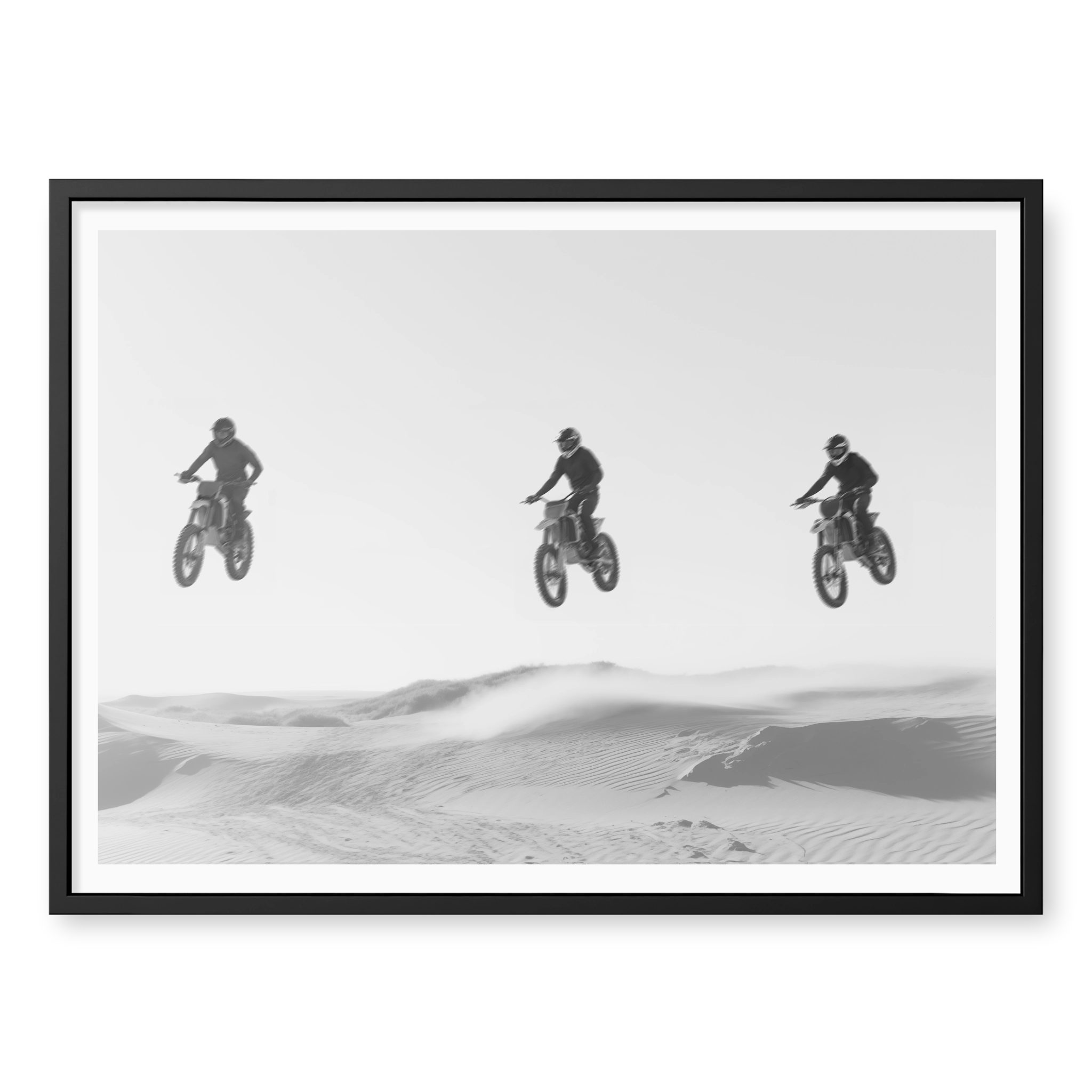 Three motocross riders jumping in a row over sand dunes, black and white art print titled Amigos in black frame