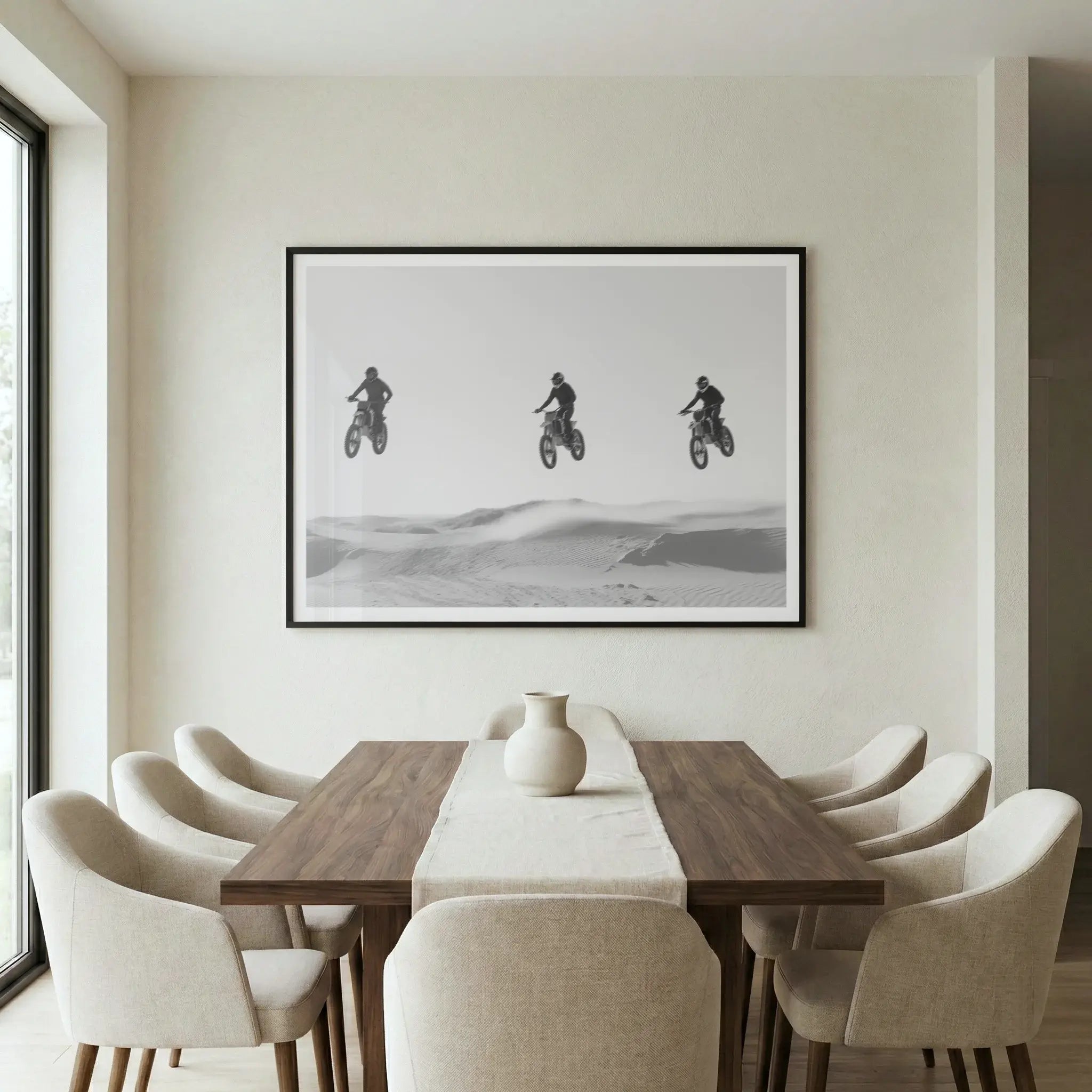 Framed black and white art print with three motocross riders jumping in a row, titled Amigos displayed in dining room
