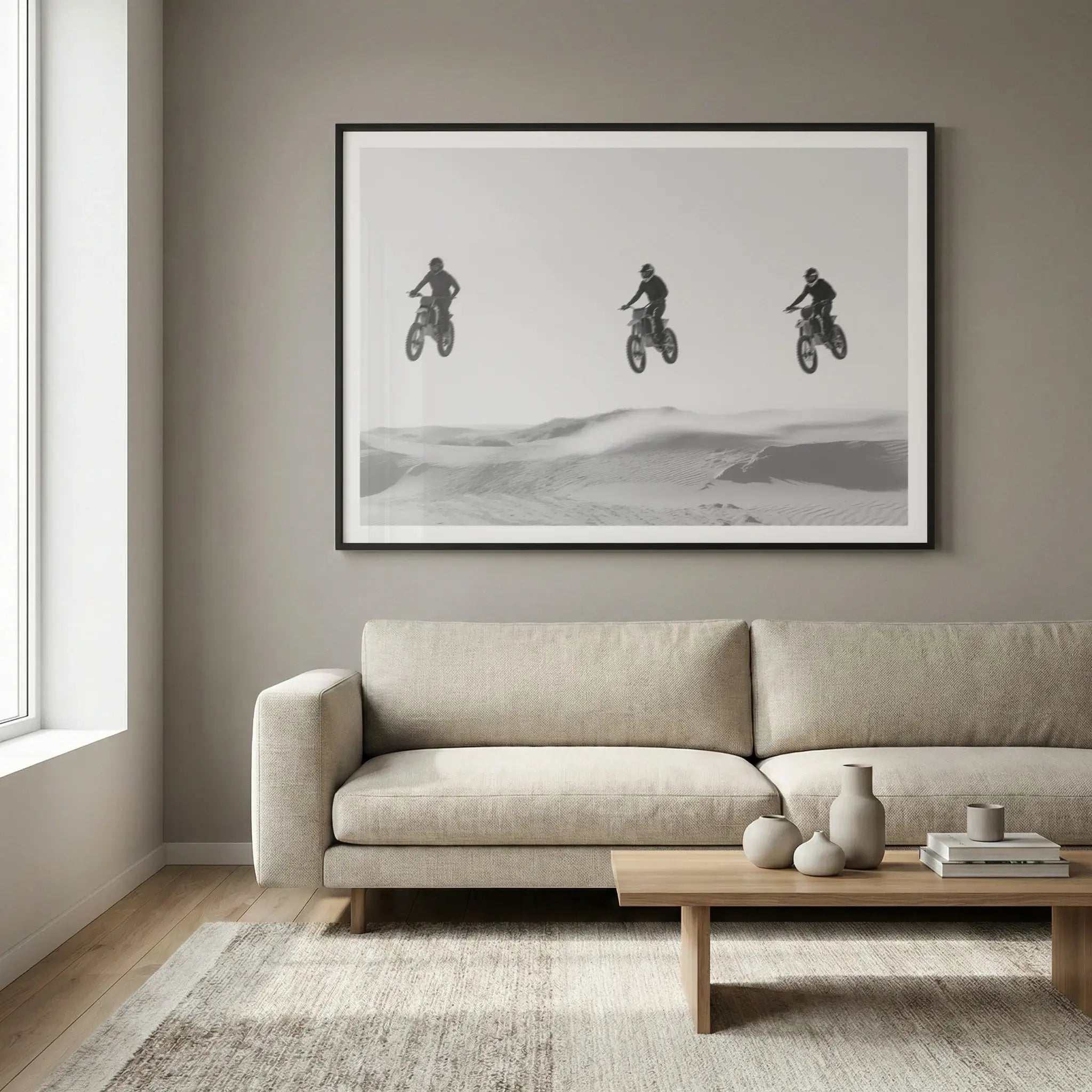 Framed black and white art print with three motocross riders jumping in a row, titled Amigos displayed in living room