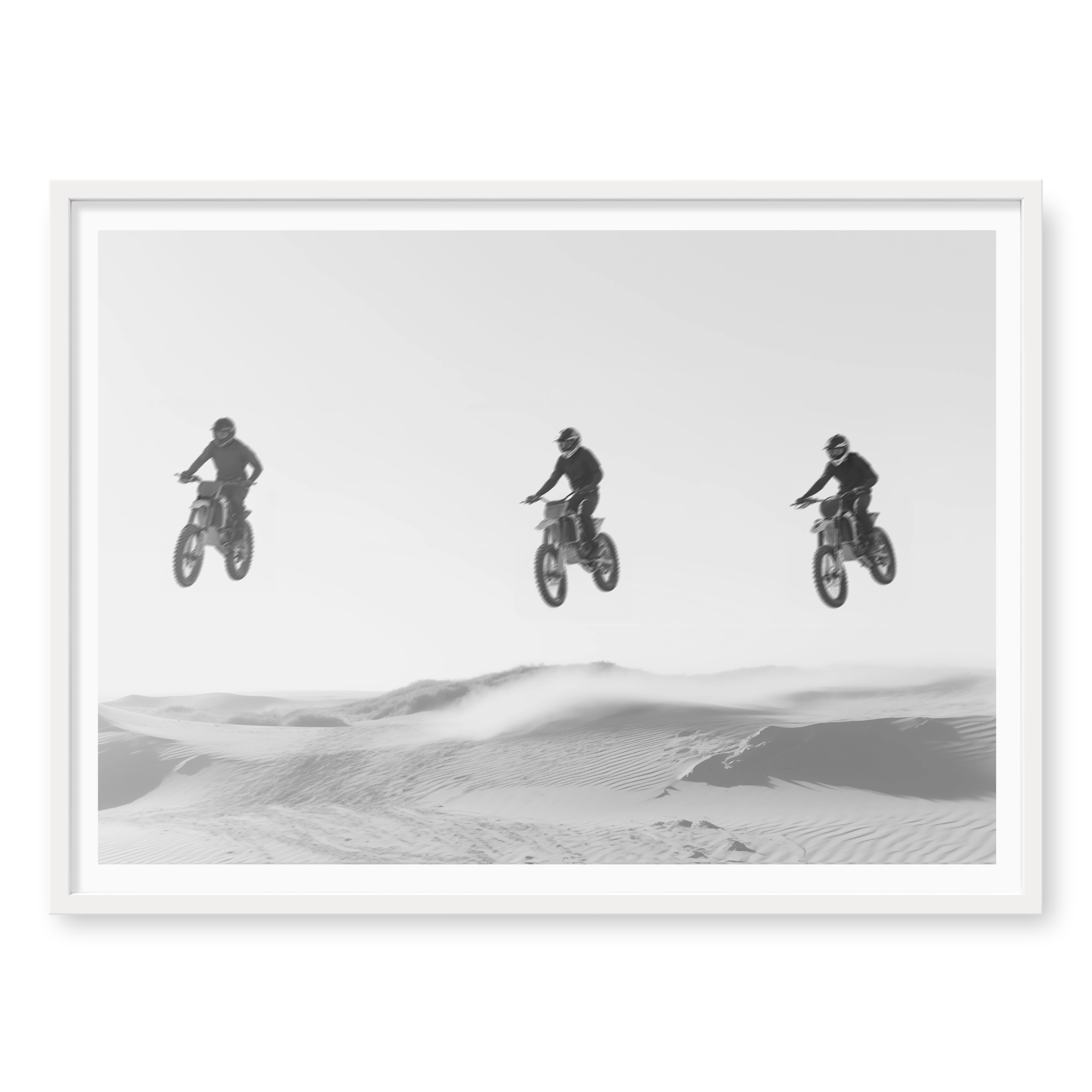 Three motocross riders jumping in a row over sand dunes, black and white art print titled Amigos in white frame