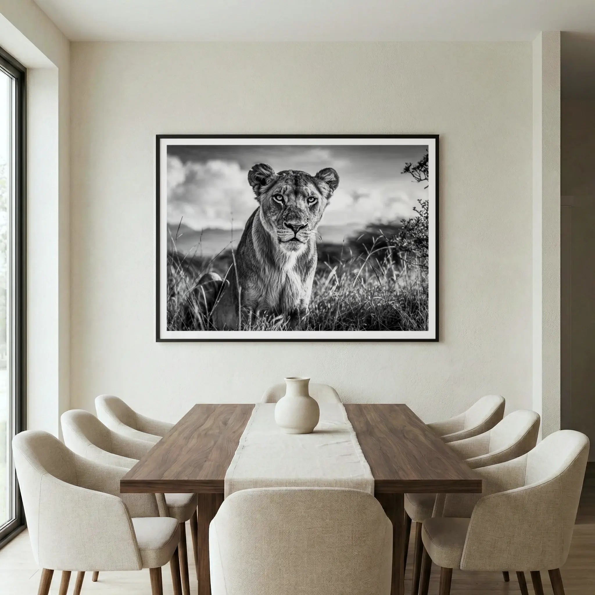 Framed black and white art print with lioness sitting in tall grass, titled Aphrodite displayed in dining room
