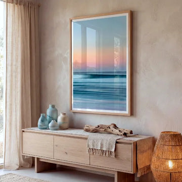 Framed seascape artwork with soft sunset tones displayed above a wooden sideboard.