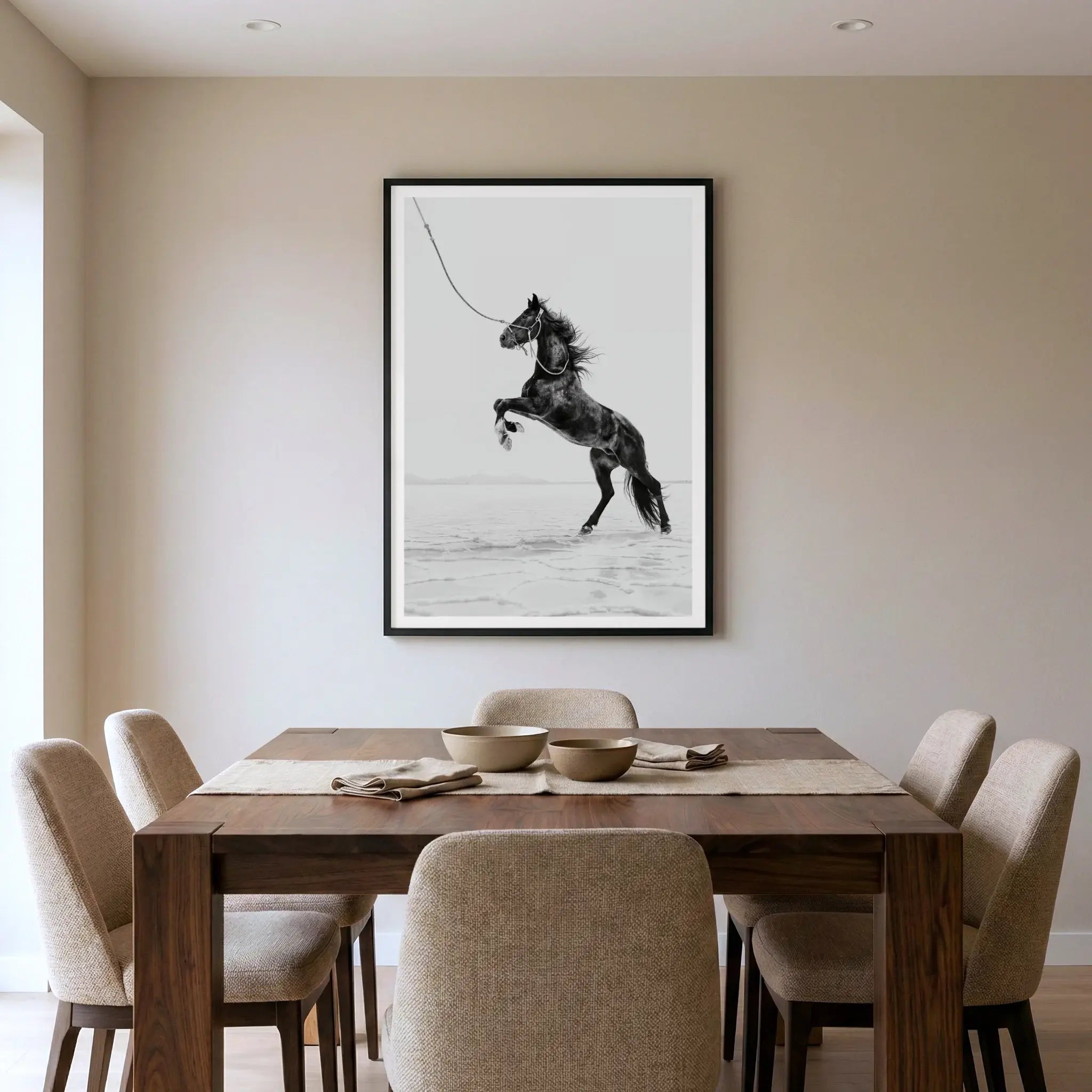 Framed black and white art print with dark horse rearing on salt flats, titled Born Wild displayed in dining room