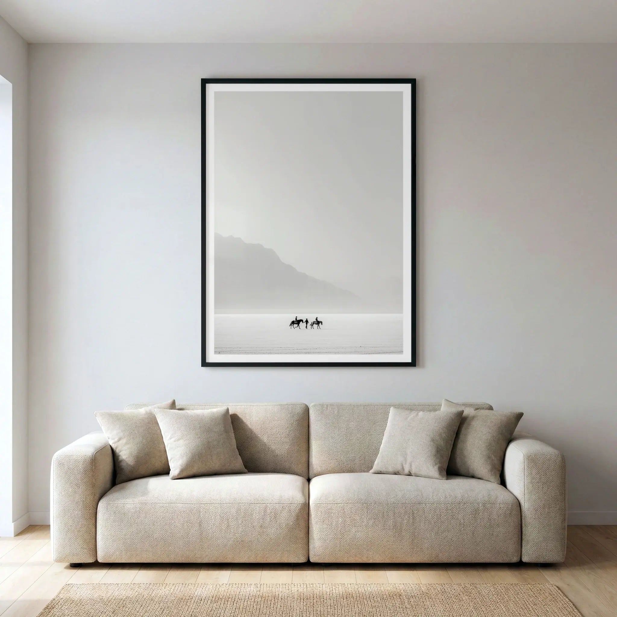 Framed minimalist art print with tiny riders on horseback in a white desert, titled Destination Unknown displayed in living room