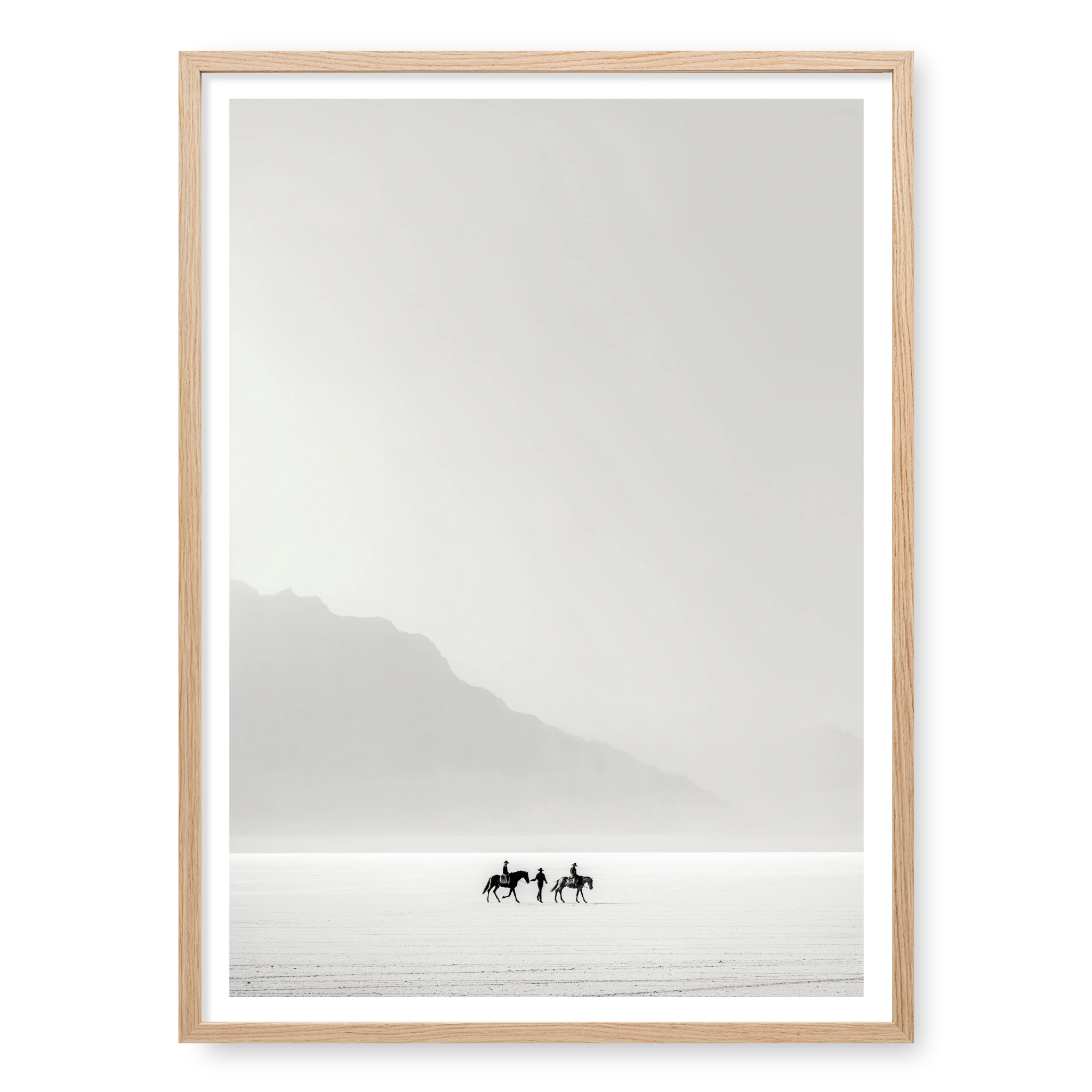 Tiny silhouettes of riders on horseback journeying across a vast white desert landscape, art print titled Destination Unknown in natural oak frame
