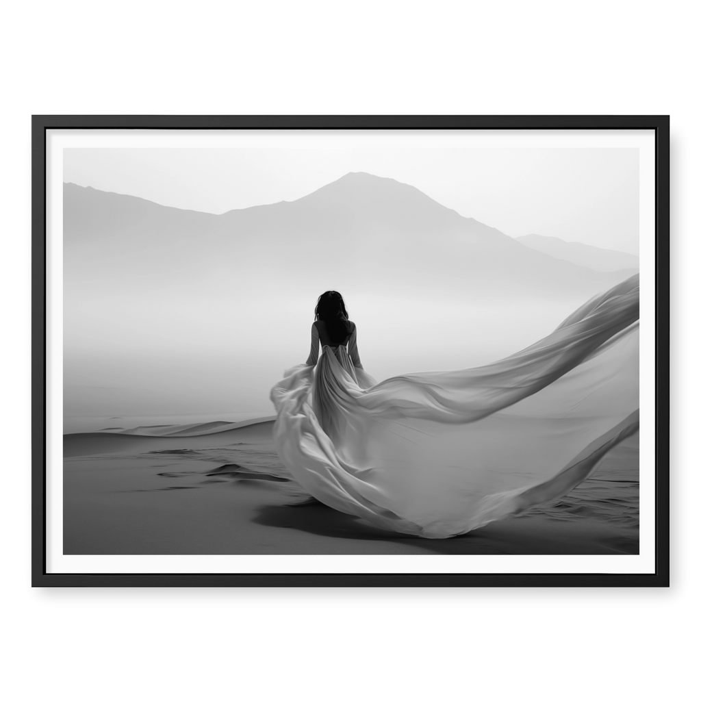 Rear view of woman in a long flowing dress walking across sand dunes towards misty mountains, black and white art print titled Freedom in black frame