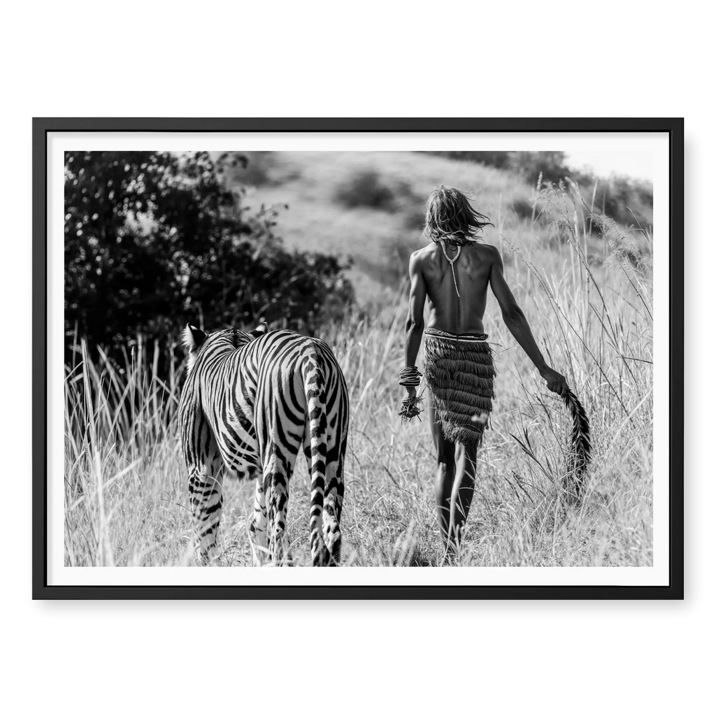 Rear view of a man in traditional attire walking alongside a tiger through tall grass, black and white art print titled Life of Pi in black frame