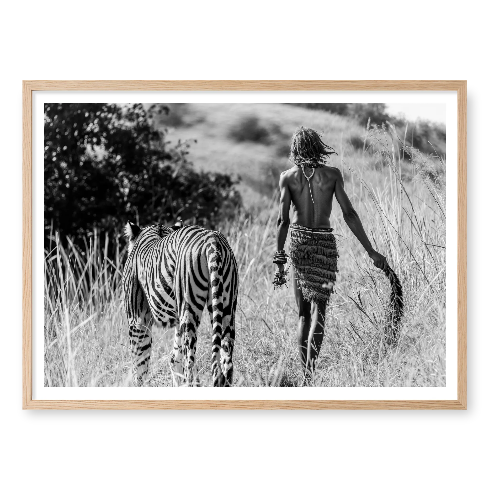 Rear view of a man in traditional attire walking alongside a tiger through tall grass, black and white art print titled Life of Pi in natural oak frame