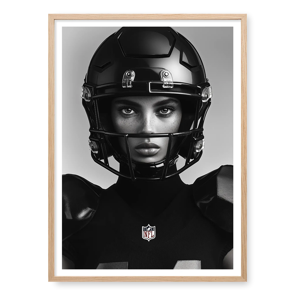 Close-up front-facing portrait of a female American football player wearing a glossy black helmet and pads with the NFL logo, black and white art print titled Modern Gladiator in natural oak frame