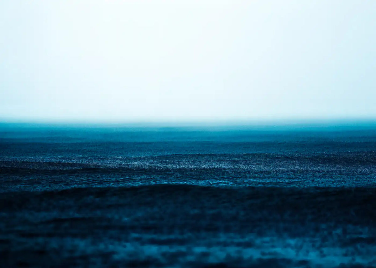 Minimal blue ocean seascape fading into a pale misty sky, displayed as black-framed landscape wall art.