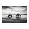 Panning shot of two riders on motorcycles racing along a wet beach with motion blur effect, black and white art print titled Partners
