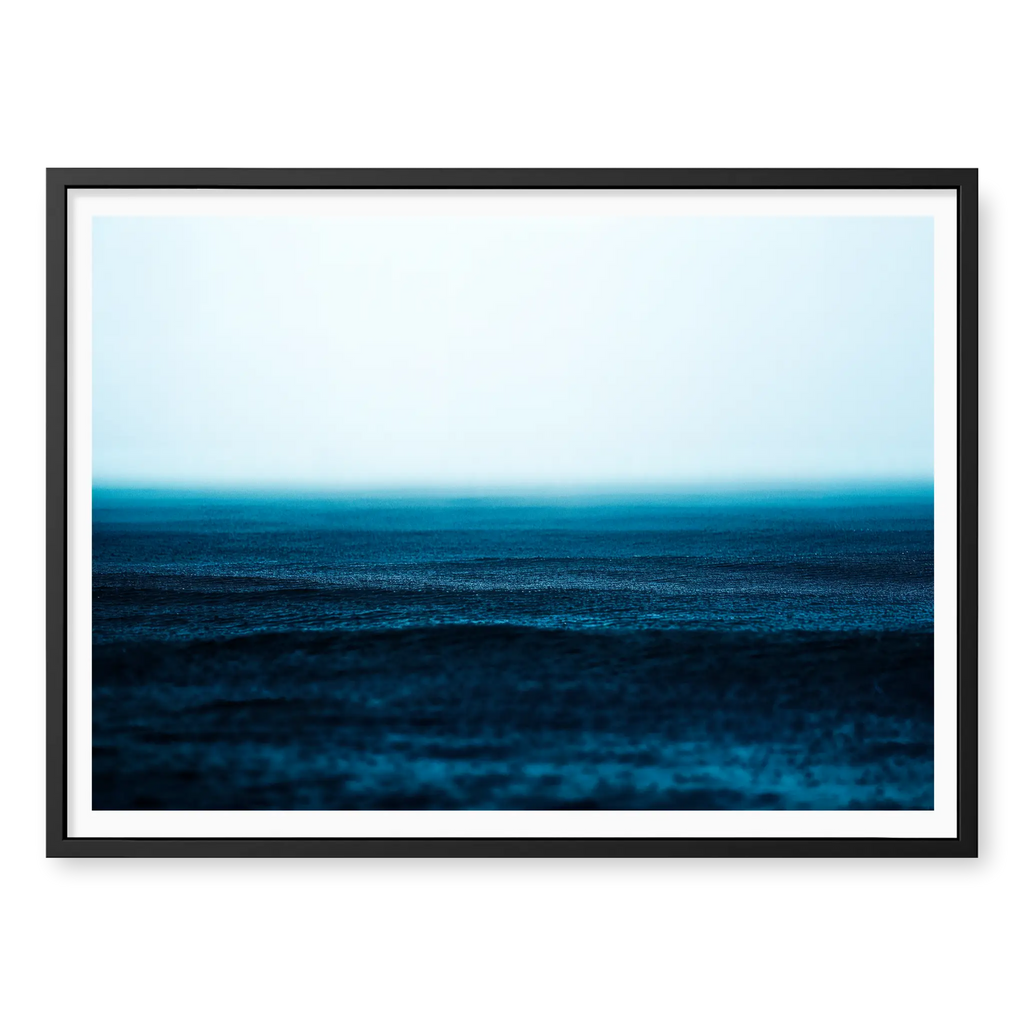 Minimalist seascape with deep blue water textured by falling rain fading into a misty white horizon, art print titled Petrichor in black frame