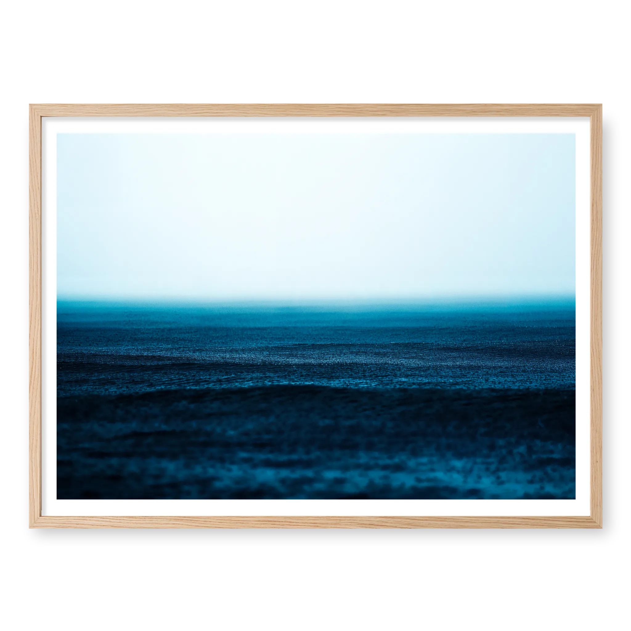 Minimalist seascape with deep blue water textured by falling rain fading into a misty white horizon, art print titled Petrichor in natural oak frame