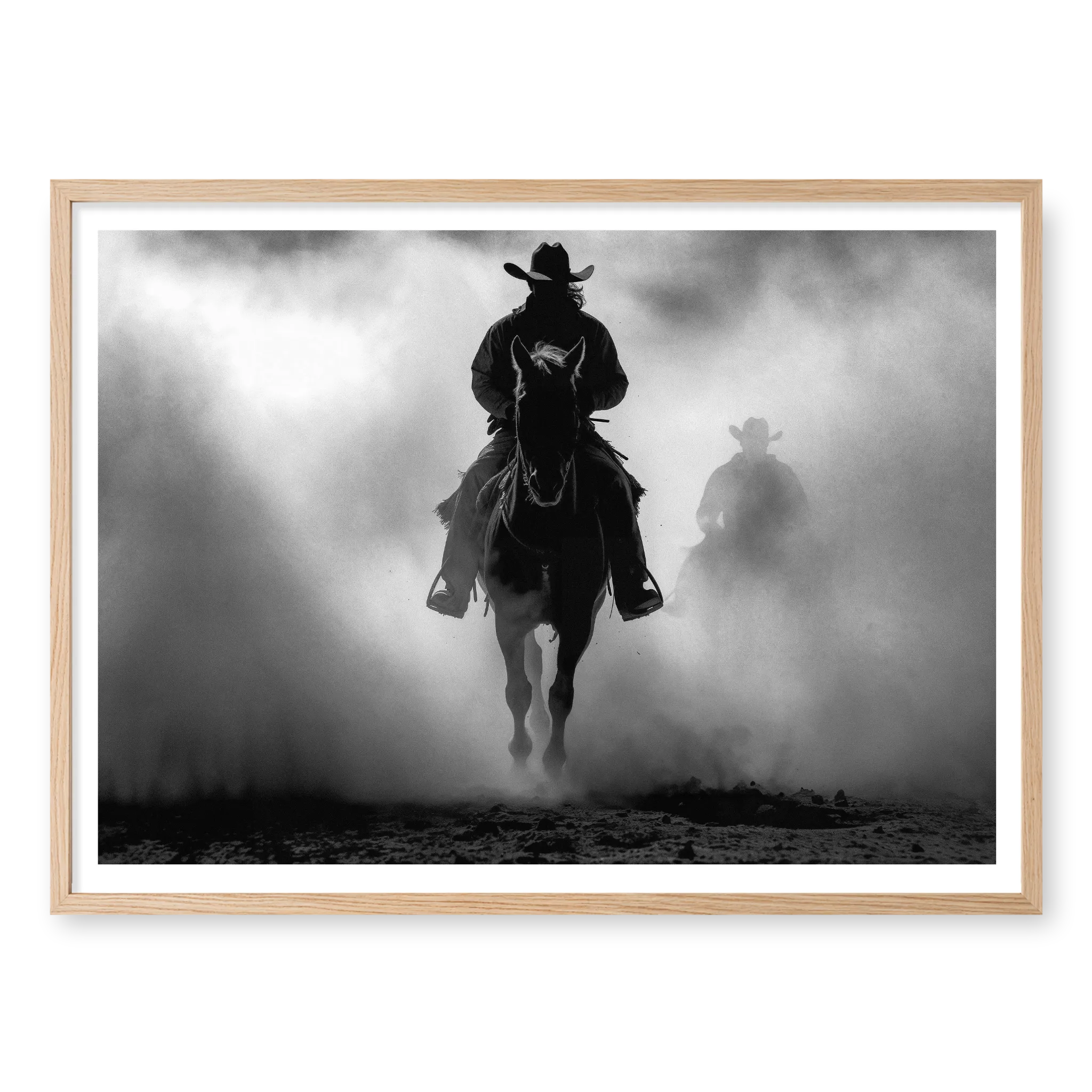 Silhouette of a cowboy riding a horse head-on through thick dust and fog, with a second rider fading into the background, black and white art print titled Searchers in natural oak frame