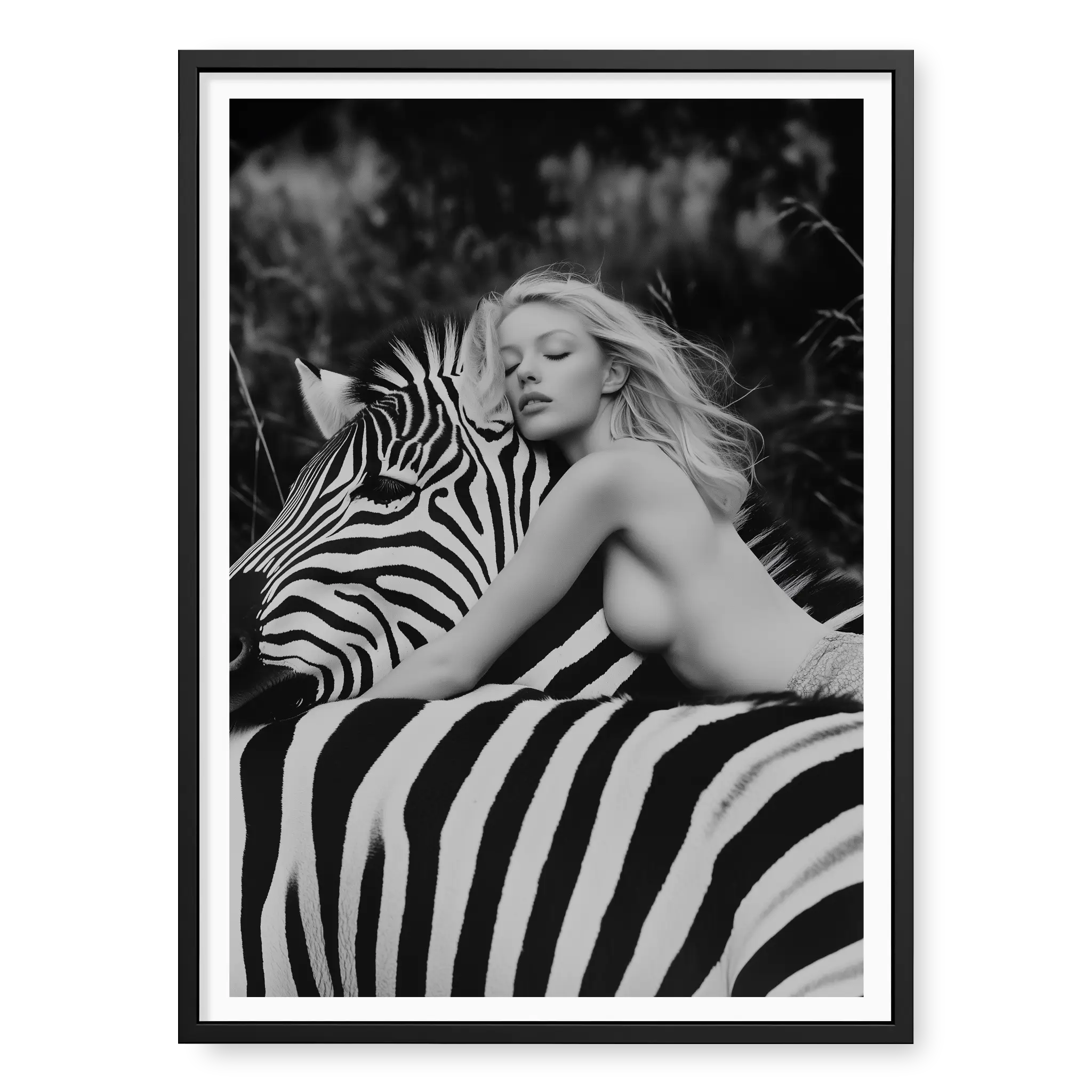 Close-up black and white fine art print of a blonde woman leaning forward with her head resting gently on the neck of a zebra, titled Stripes in black frame