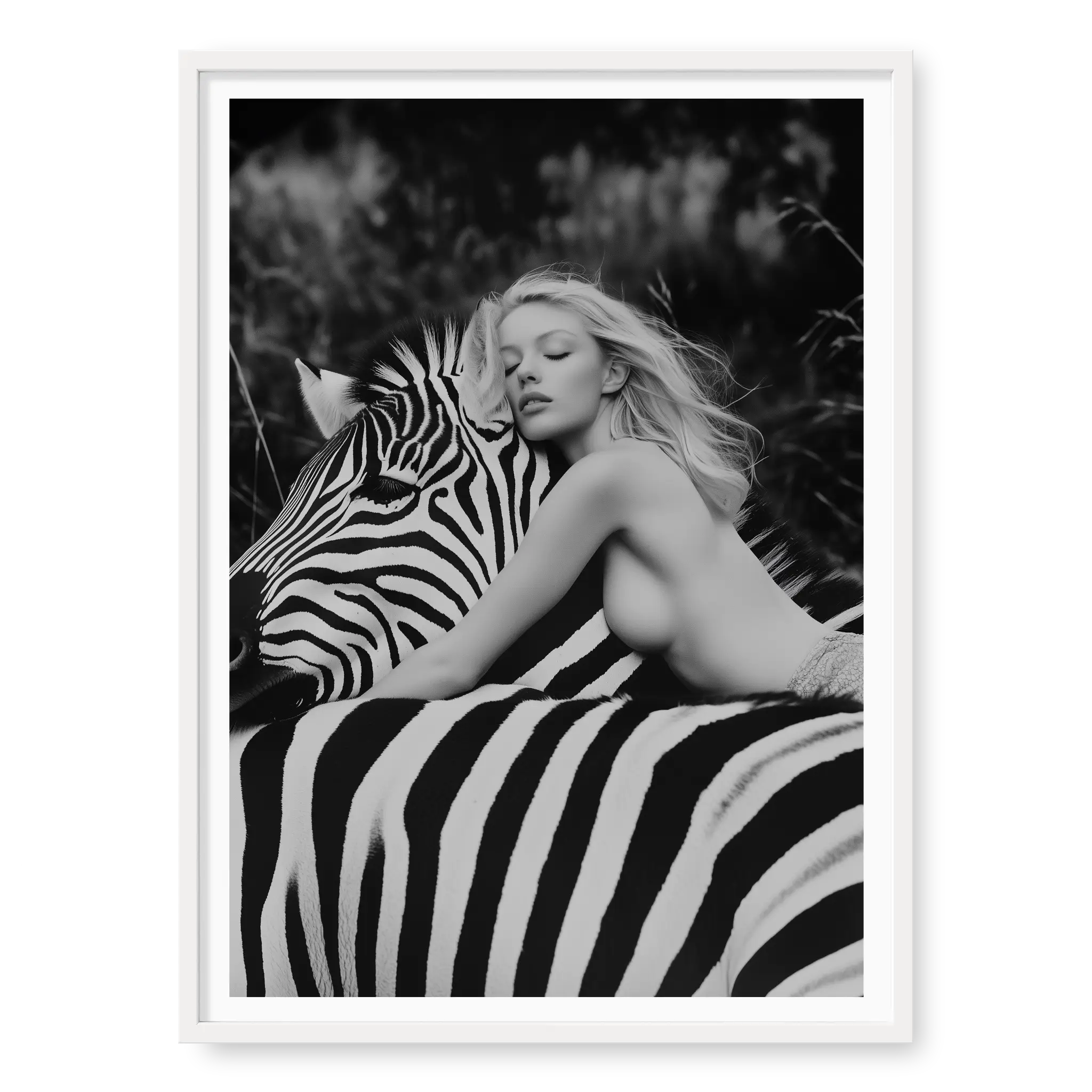 Close-up black and white fine art print of a blonde woman leaning forward with her head resting gently on the neck of a zebra, titled Stripes in white frame