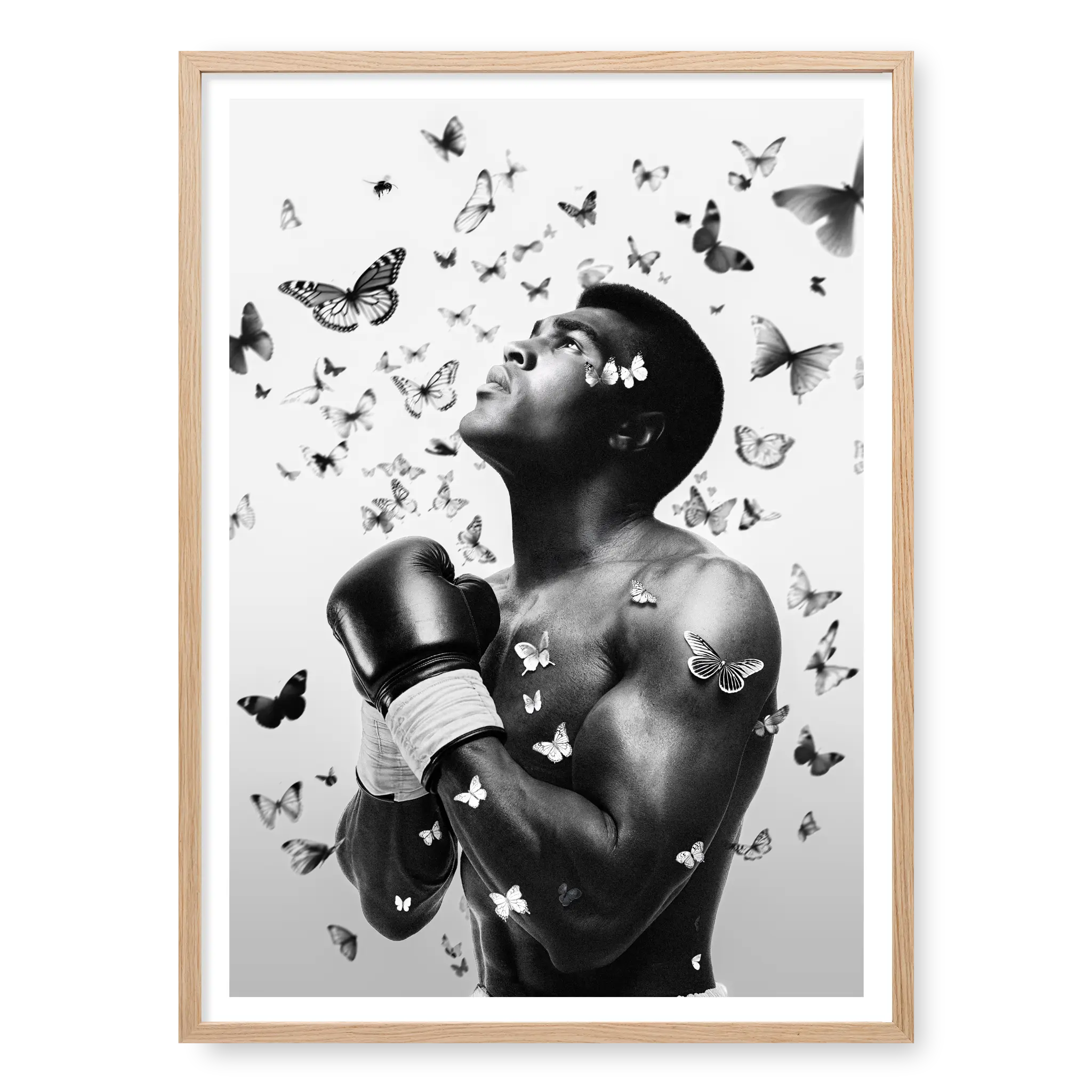 Side profile portrait of Muhammad Ali looking upwards with boxing gloves raised, surrounded by a swarm of flying butterflies, black and white art print titled The Greatest in natural oak frame
